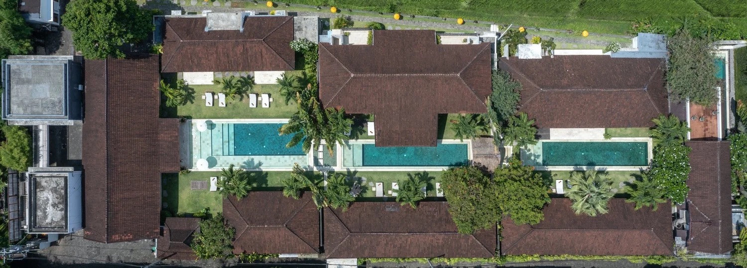 Aerial view of three villas with pools and lawns backing onto rice fields at Abaca Villas, Petitenget, Seminyak
