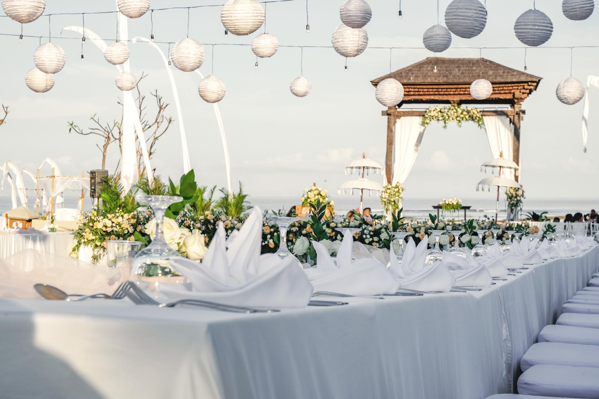 Beach wedding setup with a Balinese gazebo and hanging lanterns facing the ocean at Ayodya Resort Bali, Nusa Dua