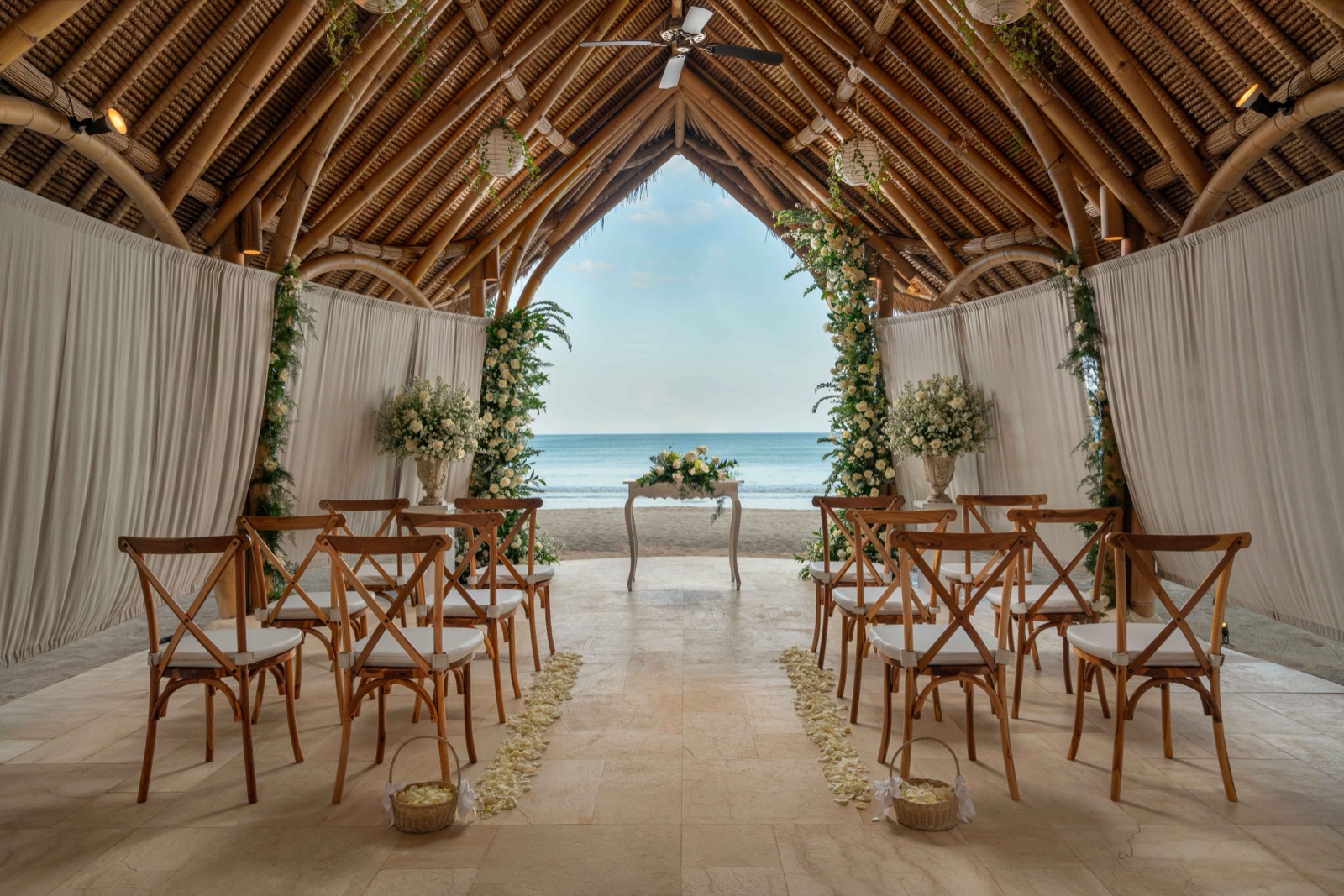 The open bamboo pavilion at Belmond Jimbaran Puri looking out to Jimbaran beach and the sea, set for a wedding ceremony