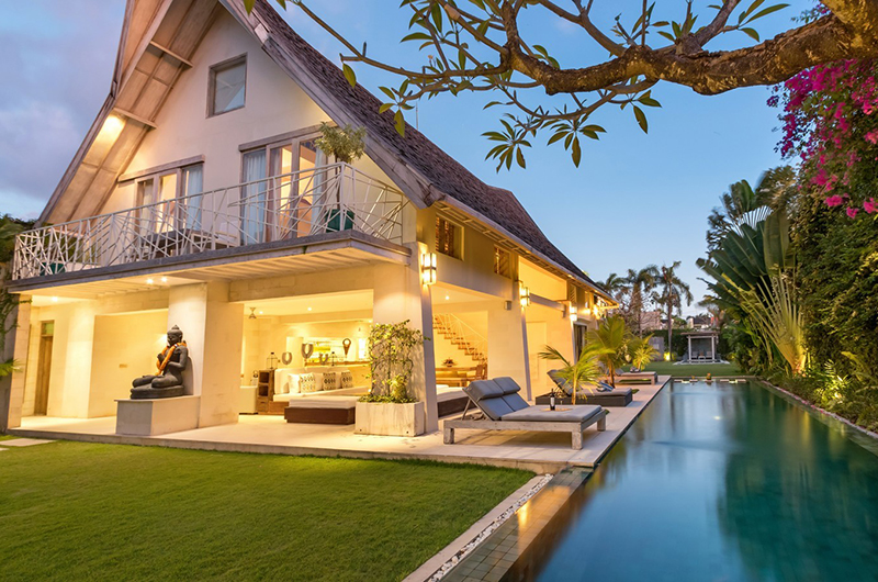 Villa Casa Mateo lit at dusk with its lap pool, lawn, and open pavilion in central Seminyak, Bali