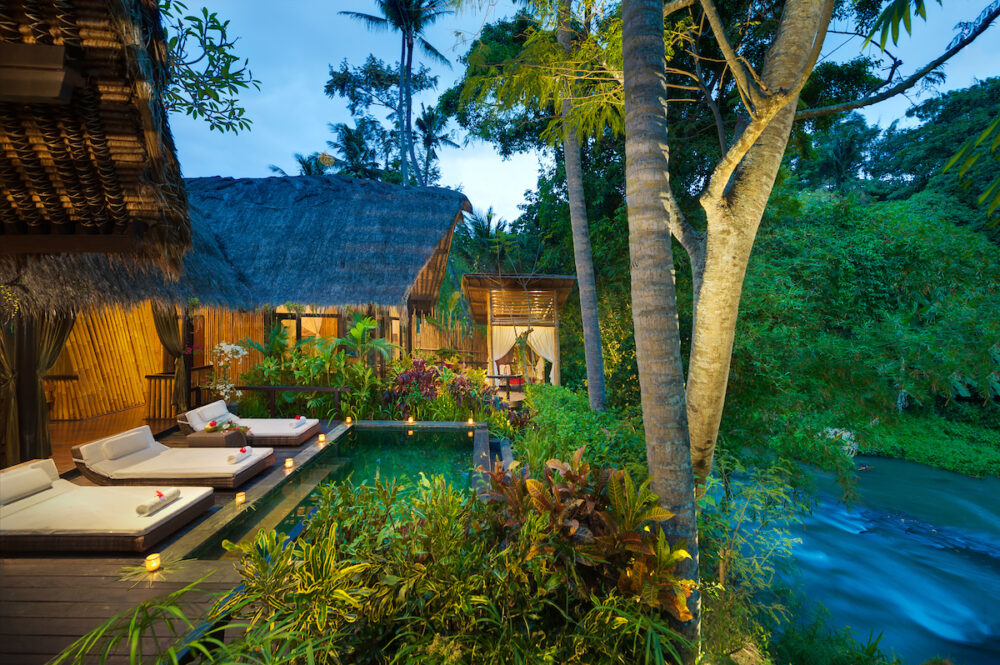 A riverfront bamboo suite and private pool at Fivelements Retreat Bali at dusk, overlooking the Ayung River and jungle near Ubud