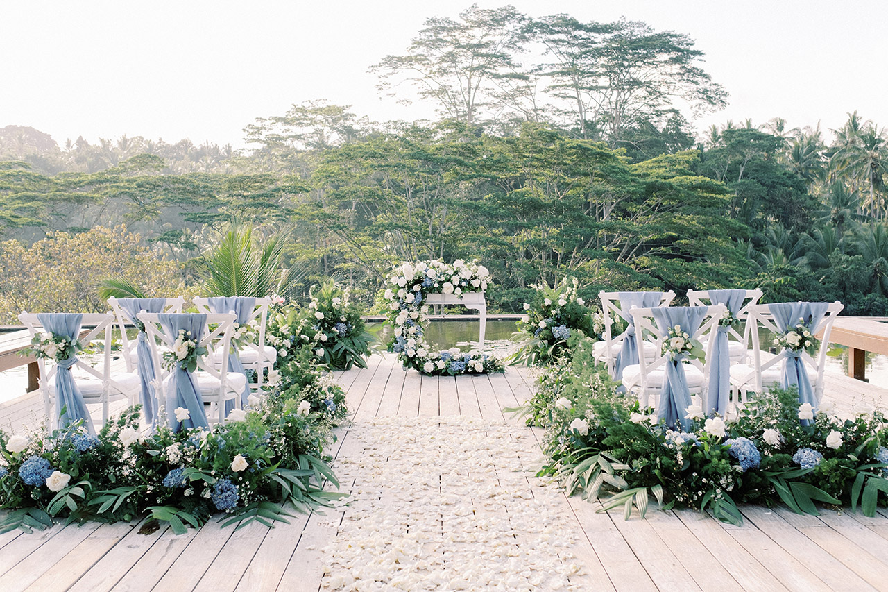 A wedding ceremony set up on the Rooftop Lotus Pond terrace at Four Seasons Resort Bali at Sayan, with white and blue florals and the Ayung River jungle behind
