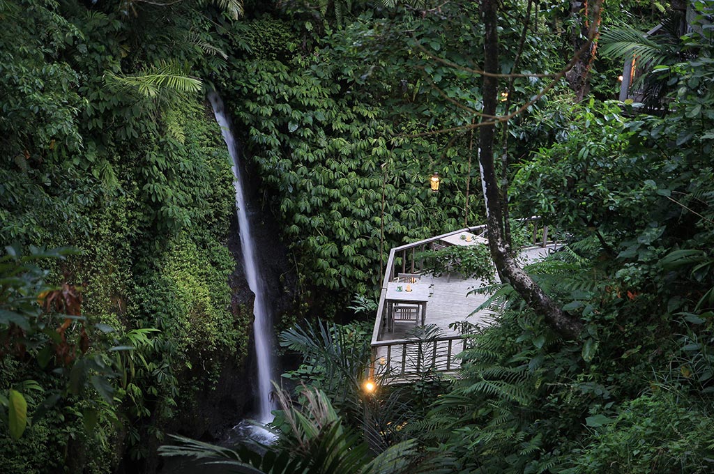 A dining deck beside a jungle waterfall at The Kayon Resort by Pramana, in the valley near Ubud