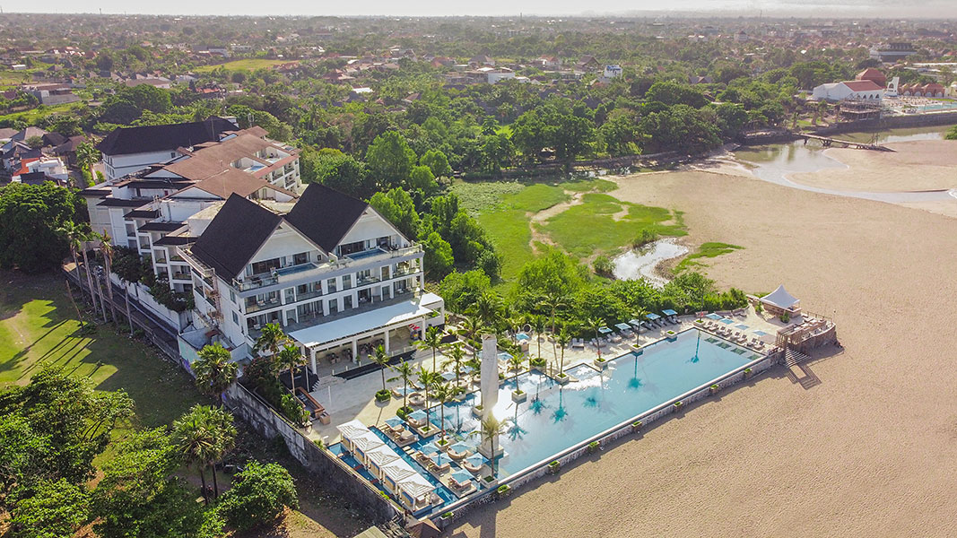 Aerial view of Lv8 Resort Hotel with beachfront pool, white suites, and Berawa Beach, Canggu