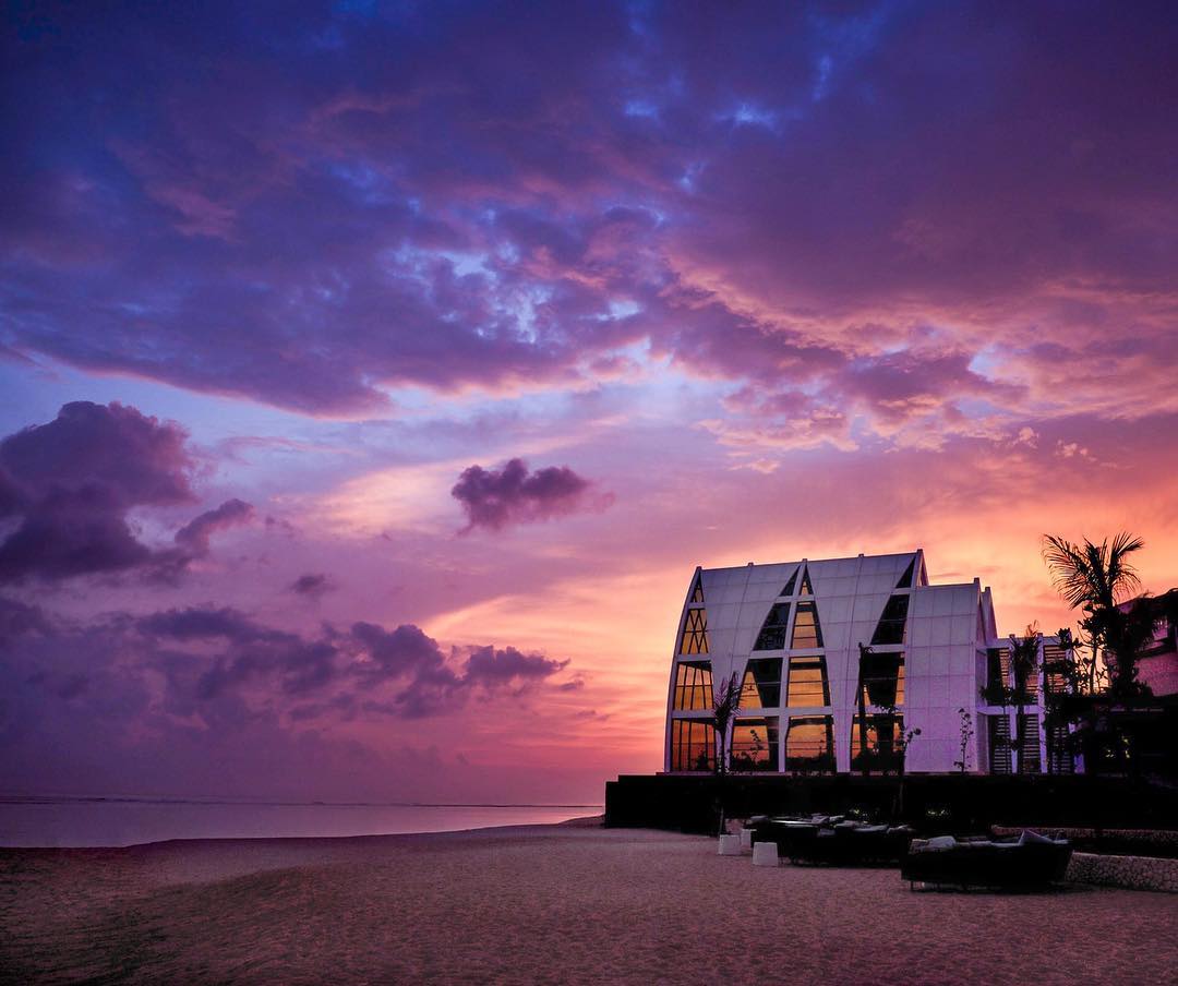The glass Majestic Chapel at The Ritz-Carlton Bali on Sawangan Beach at sunset, facing the Indian Ocean