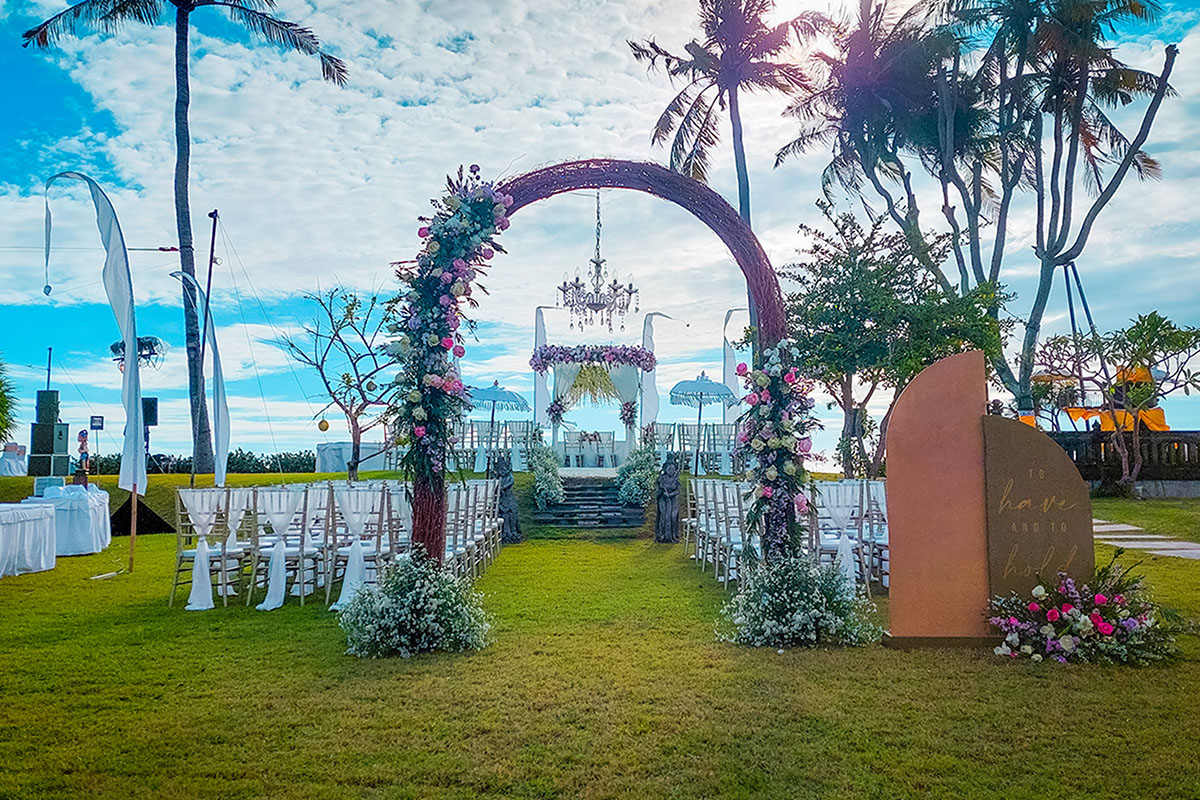 The garden wedding lawn at The Patra Bali Resort & Villas set for a ceremony, palms and resort grounds around it