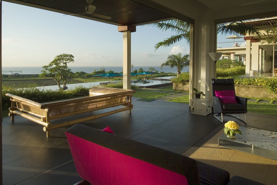 Covered outdoor pavilion with lounge seating at Sanur Residence, opening onto the garden and pool
