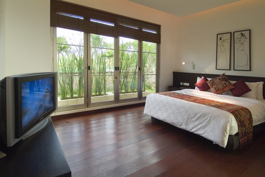 Bedroom at Sanur Residence with glass doors opening onto a private garden view