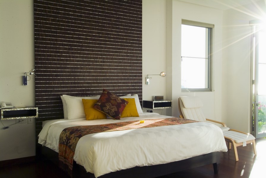 Bedroom at Sanur Residence with a carved wood headboard and traditional ikat textiles
