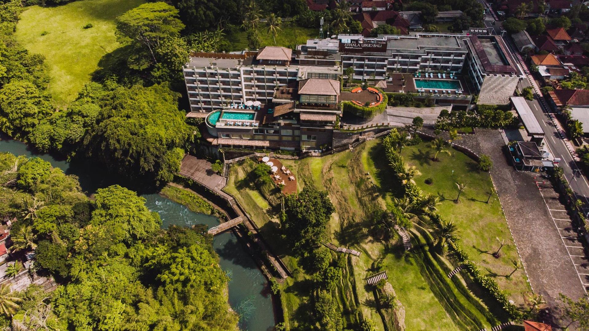 Aerial view of Sthala, a Tribute Portfolio Hotel in Ubud Bali, on a hilltop above the Wos River with terraced gardens and jungle around it
