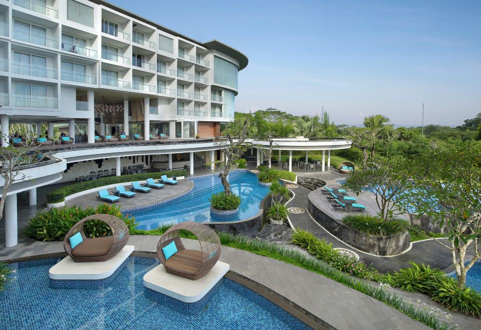 The pool terrace and main building of Swiss-Belresort Pecatu, with daybeds and gardens on the Bukit peninsula in Pecatu, Bali