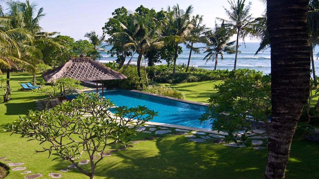 Villa Arika's beachfront garden with pool, palm trees and ocean views in Canggu
