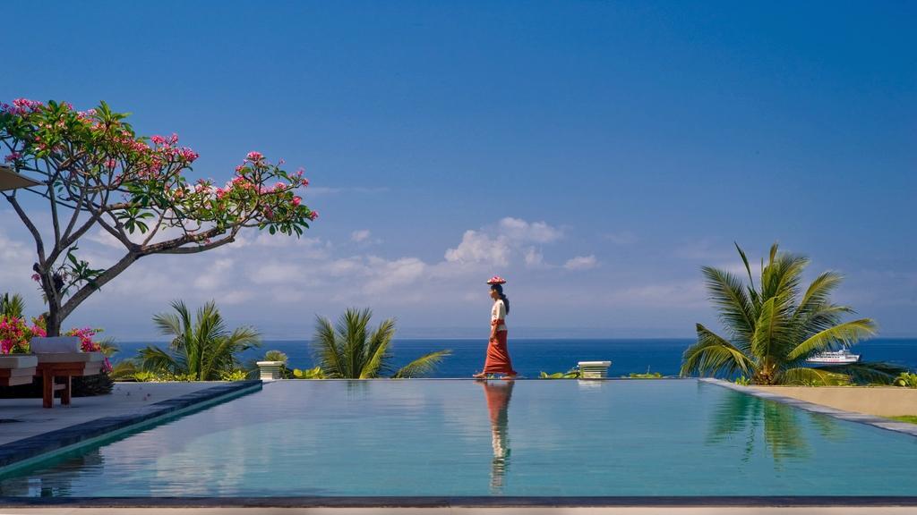 A woman in traditional Balinese dress walking beside the infinity pool at Villa Asada