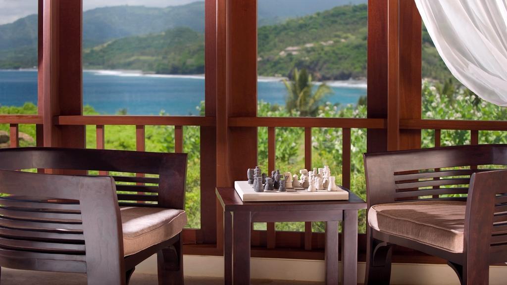 A shaded lounge corner at Villa Asada with a sea view through the balcony rail