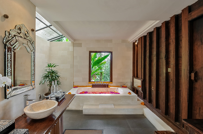 Stone bathroom at Villa Bodhi with a sunken tub scattered with flower petals