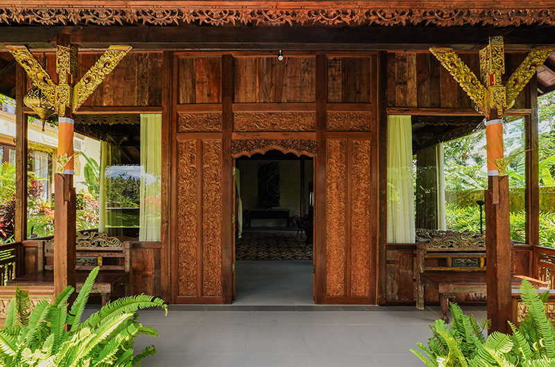 Carved teak joglo entrance at Villa Bodhi with gilded details and ferns