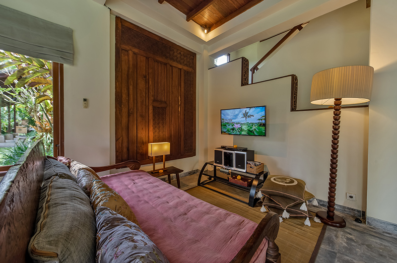 Living lounge at Villa Bodhi with a cushioned daybed, carved antique wooden door and thatched ceiling