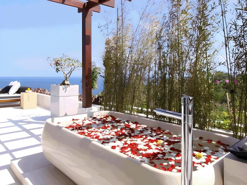 An outdoor bathtub on a terrace at Villa Cahaya, framed by bamboo with the ocean beyond