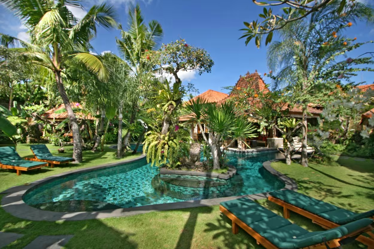 Villa Des Indes I's tropical garden and pool in front of the villa's tiled-roof pavilions in Laksmana, Seminyak