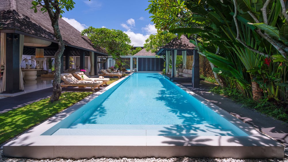 Villa Des Indes II's long pool and garden framed by an open joglo pavilion in Laksmana, Seminyak