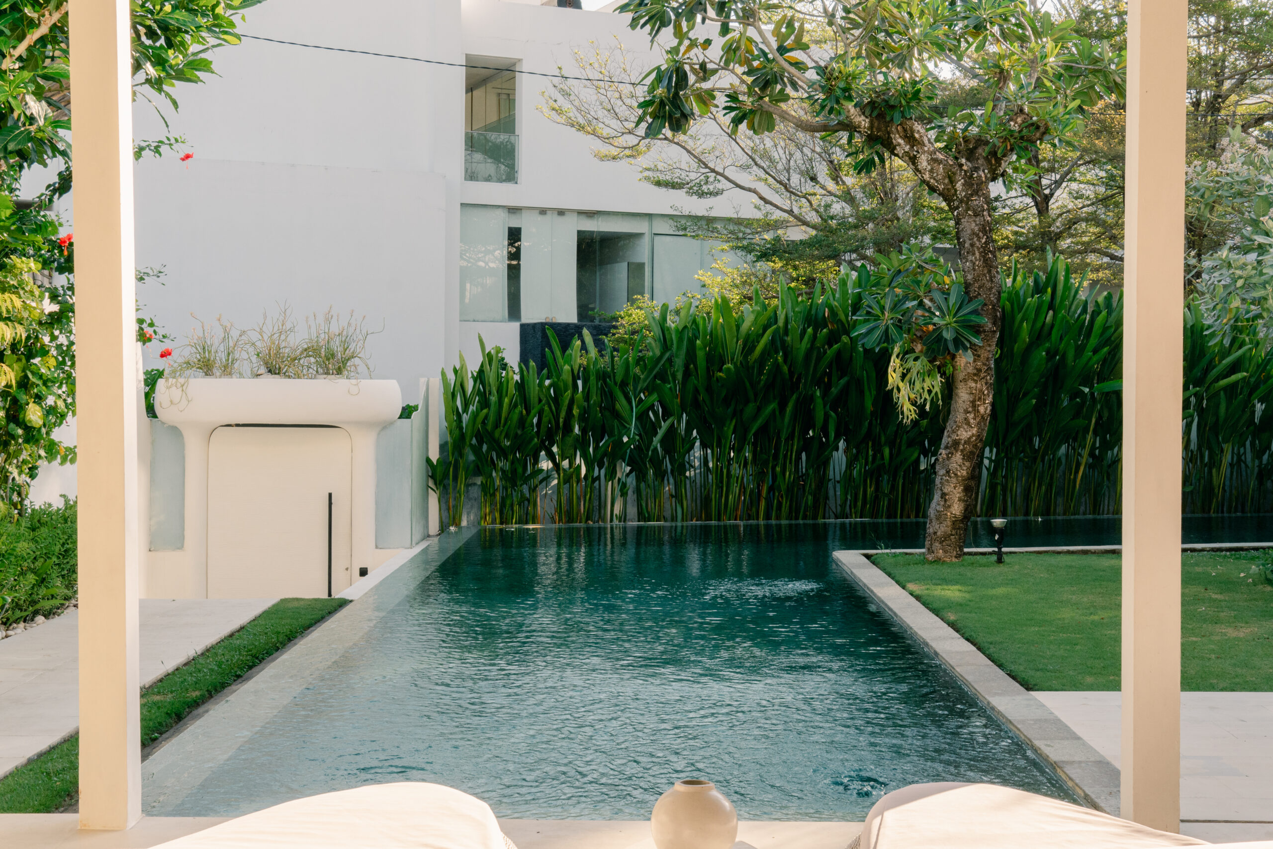 Villa Eden's pool and tropical garden with the white villa behind, at Eden The Residence at The Sea, Seminyak