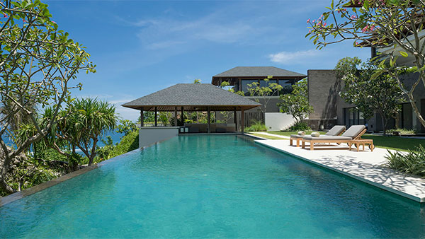The infinity pool and thatched living pavilion at Villa Hamsa on a clifftop above the Indian Ocean, framed by frangipani trees on the Bukit peninsula