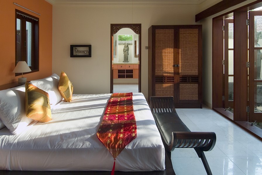 Balinese-styled bedroom at Villa Indah Manis with warm tones and carved wood wardrobe