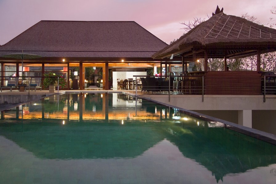 Villa Indah Manis swimming pool and thatched-roof bar pavilion lit up at dusk