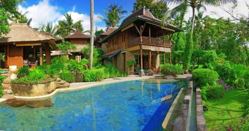 The pool and timber pavilions of Villa Kirana set among tropical gardens near Ubud, Bali