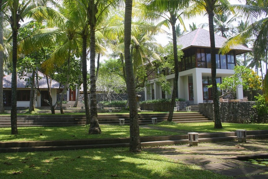 Villa Lalang's two-storey villa building framed by palm trees across the lawn