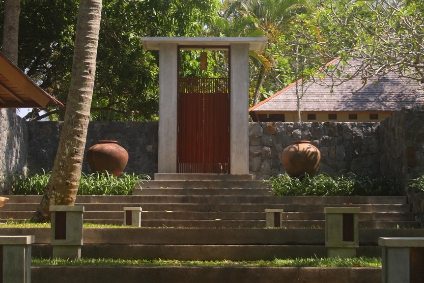 The red-doored entrance gateway to Villa Lalang, flanked by stone walls and clay urns