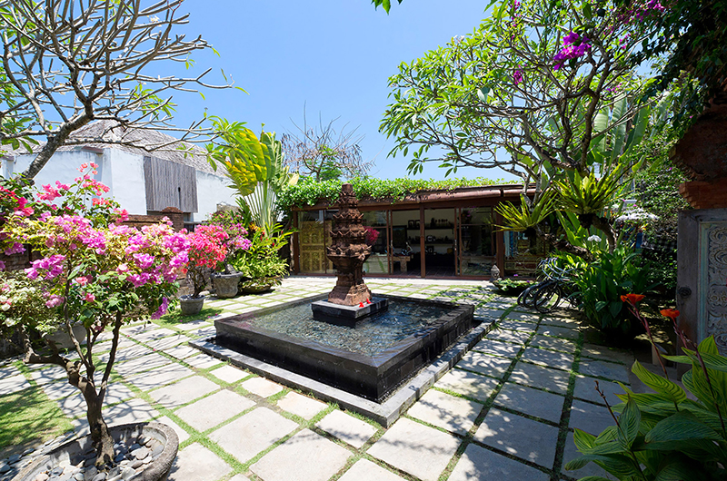 Garden courtyard with a stone water feature and bougainvillea at Majapahit Beach Villas