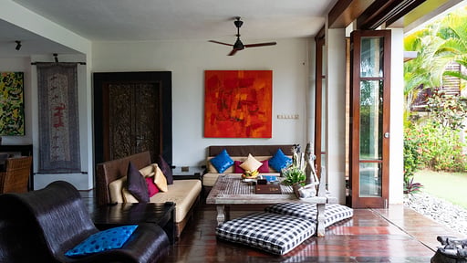Open-air living room with Balinese art and daybeds opening onto the garden at Villa Majapahit Nataraja