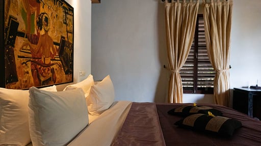 Second bedroom dressed with local artwork and soft curtains at Villa Majapahit Nataraja