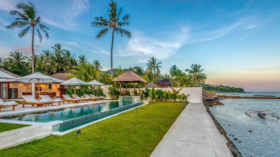 Wide view of Villa Oceana's pool, gazebo, and the sea beyond at dusk