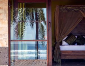 Open dining pavilion at Villa Pushpapuri looking out through glass walls to the garden, a Balinese bird carving and the ocean beyond