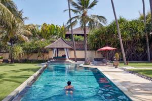 Sitting room at Villa Pushpapuri with a long cushioned daybed, bookshelves and a garden view