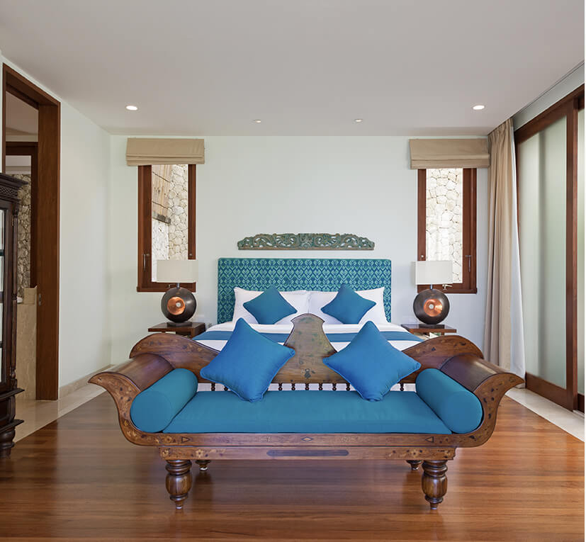 Bedroom at Villa Rose with a carved wooden daybed and blue cushions