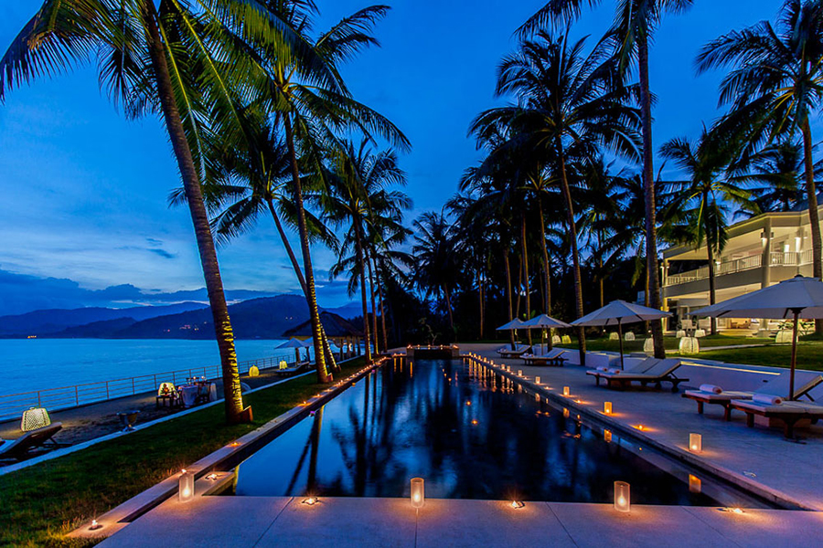 Villa Stella's pool lit with candles along the waterline at dusk
