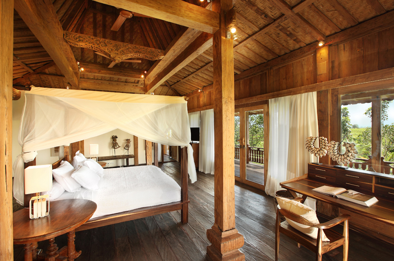 A teakwood master bedroom at Villa Tangguntiti with a four-poster canopy bed and a balcony over the rice fields